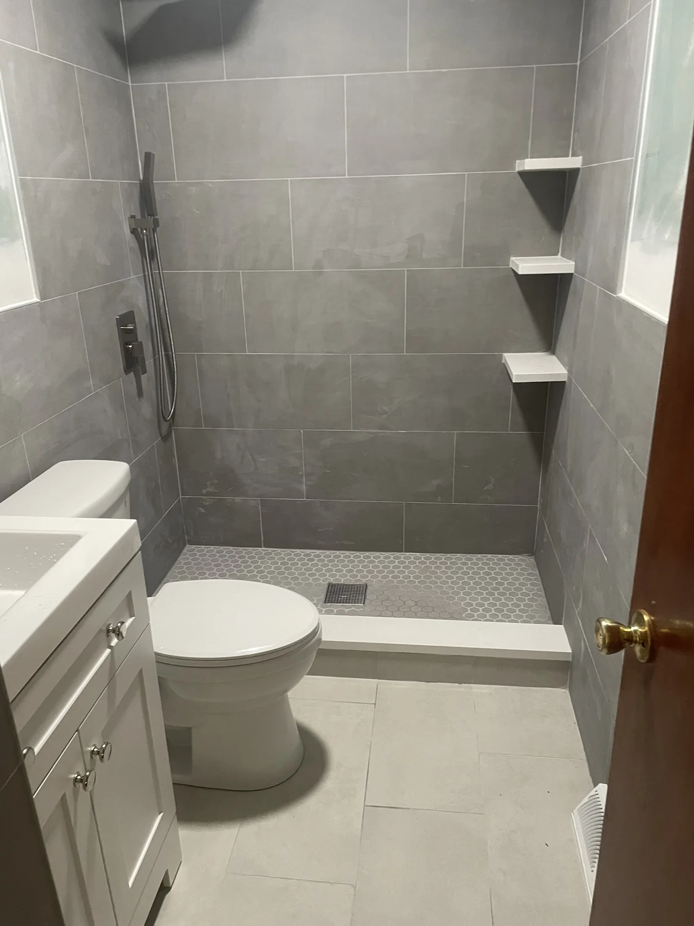 Bathroom with large gray shower tile and built-in corner shelves