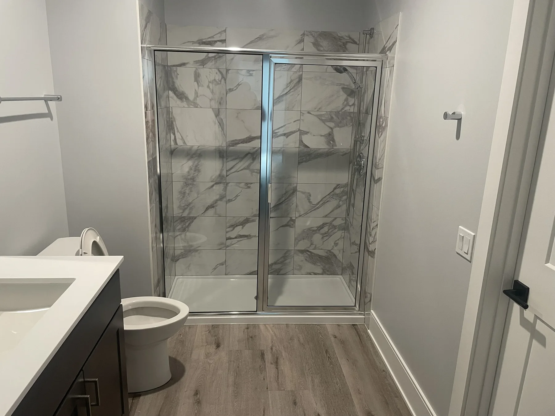 Remodeled bathroom with marble-look shower tile and glass enclosure