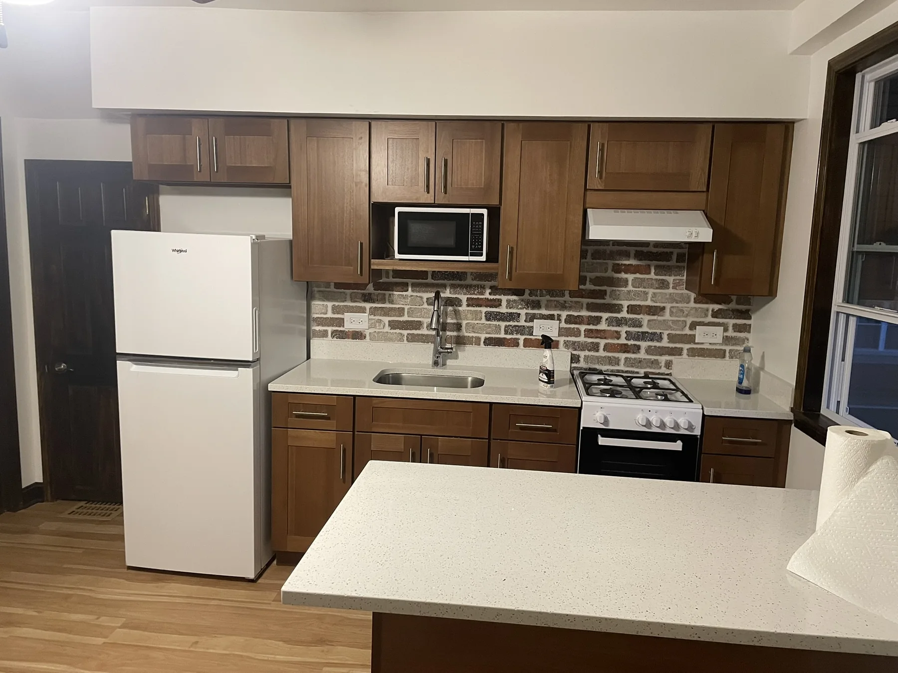 Remodeled kitchen with warm wood cabinets and brick backsplash