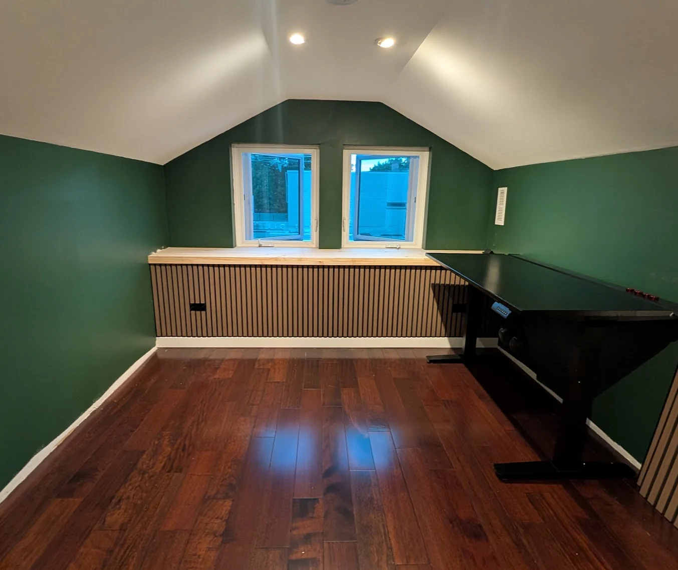 Finished green room with trimmed windows and wood slat paneling